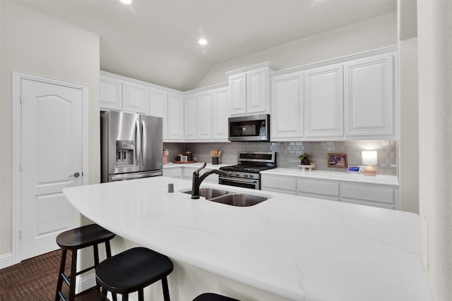 513 Endicott Dr, Sherman, TX 75092 - kitchen with appliances with stainless steel finishes, decorative backsplash, a breakfast bar, white cabinets, and vaulted ceiling