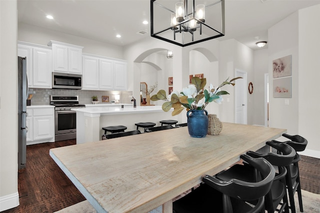 513 Endicott Dr, Sherman, TX 75092 - kitchen with stainless steel appliances, a kitchen breakfast bar, white cabinets, decorative backsplash, and recessed lighting
