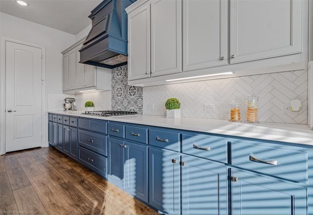 2010 Topaz Dr, Rockwall, TX 75087 - kitchen featuring custom exhaust hood, blue cabinetry, stainless steel gas cooktop, light countertops, and tasteful backsplash