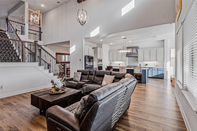2010 Topaz Dr, Rockwall, TX 75087 - living room featuring a chandelier, a towering ceiling, stairs, wood finished floors, and recessed lighting