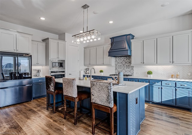2010 Topaz Dr, Rockwall, TX 75087 - kitchen with appliances with stainless steel finishes, blue cabinets, custom exhaust hood, a kitchen bar, and tasteful backsplash