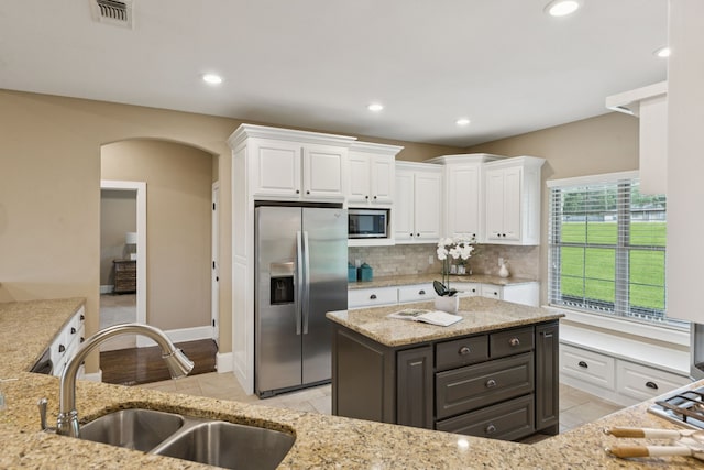 320 Tate Cir, Sherman, TX 75090 - kitchen featuring appliances with stainless steel finishes, white cabinetry, decorative backsplash, arched walkways, and recessed lighting