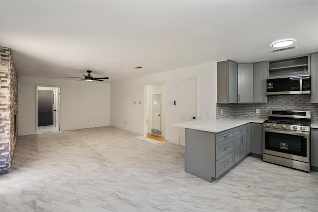 1228 Brookside Dr, Hurst, TX 76053 - kitchen with appliances with stainless steel finishes, gray cabinets, a peninsula, a ceiling fan, and decorative backsplash