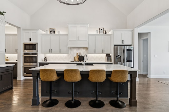 3364 Waverly Dr, Celina, TX 75009 - kitchen featuring appliances with stainless steel finishes, high vaulted ceiling, light countertops, backsplash, and an island with sink