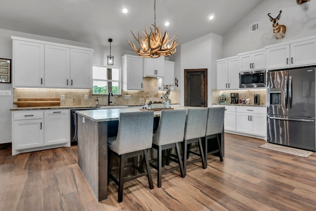 234 Pumphrey Rd, Loving, TX 76460 - kitchen featuring stainless steel appliances, a chandelier, a kitchen breakfast bar, tasteful backsplash, and white cabinets