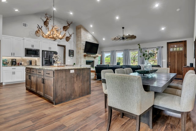 234 Pumphrey Rd, Loving, TX 76460 - dining space with high vaulted ceiling, a stone fireplace, a chandelier, wood finished floors, and recessed lighting