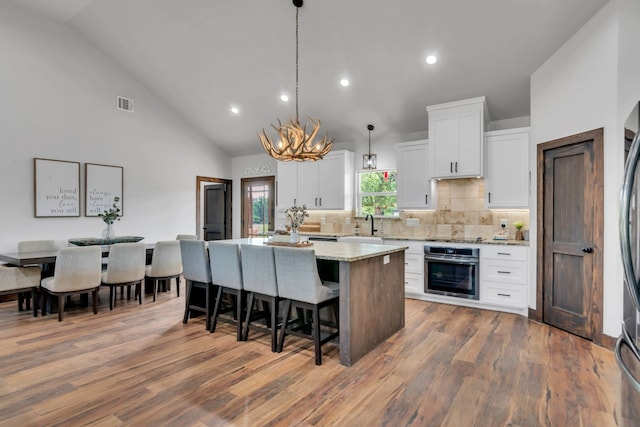 234 Pumphrey Rd, Loving, TX 76460 - kitchen featuring oven, a kitchen island, a chandelier, white cabinetry, and a kitchen breakfast bar