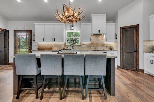 234 Pumphrey Rd, Loving, TX 76460 - kitchen with white cabinetry, a kitchen breakfast bar, tasteful backsplash, light wood finished floors, and a center island