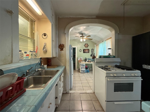 7032 Wofford Ave, Dallas, TX 75227 - kitchen featuring gas range gas stove, white cabinets, tile countertops, ceiling fan, and light tile patterned flooring