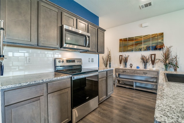 1315 Blessed Ln, Royse City, TX 75189 - kitchen featuring appliances with stainless steel finishes, dark wood-style flooring, backsplash, and light stone counters