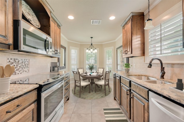 105 Windsor Dr, Forney, TX 75126 - kitchen featuring stainless steel appliances, a chandelier, light tile patterned floors, light stone countertops, and crown molding