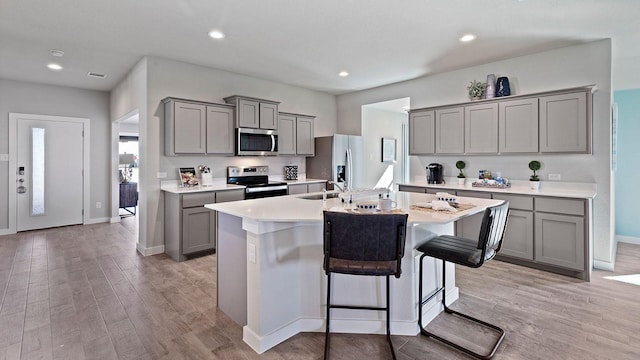 1525 Central Park Dr, Alvarado, TX 76009 - kitchen featuring stainless steel appliances, gray cabinets, a kitchen island with sink, light wood-style floors, and recessed lighting
