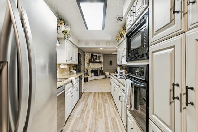 3244 Gail Ct, Irving, TX 75060 - kitchen featuring black appliances, light wood-style floors, and white cabinetry