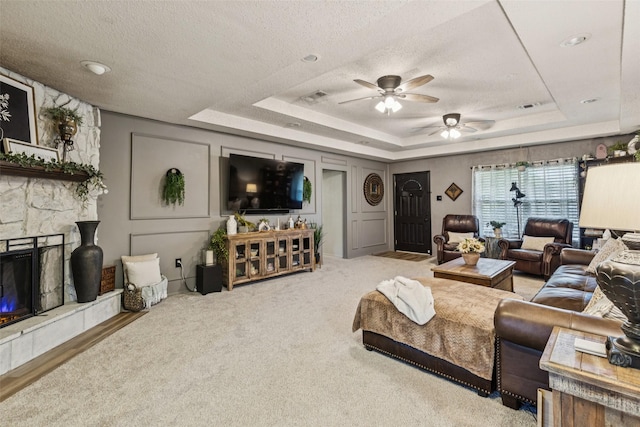 3244 Gail Ct, Irving, TX 75060 - living area with a tray ceiling, ceiling fan, a textured ceiling, and a stone fireplace
