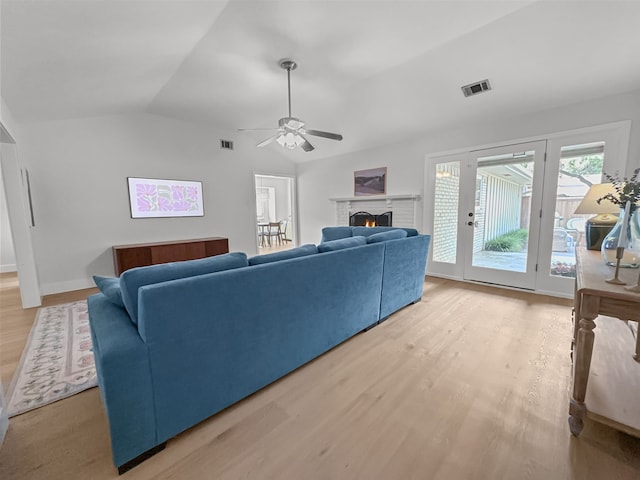 312 Meadowlark Dr, Richardson, TX 75080 - living room featuring light wood finished floors, a ceiling fan, lofted ceiling, and a brick fireplace