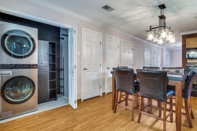 902 Travis Ave, Alvarado, TX 76009 - dining space featuring estacked washer and dryer, light wood finished floors, crown molding, and a chandelier