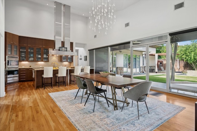 613 N Bailey Ave, Fort Worth, TX 76107 - dining space featuring a towering ceiling, light wood-style floors, a chandelier, and recessed lighting