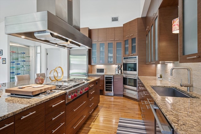613 N Bailey Ave, Fort Worth, TX 76107 - kitchen with custom range hood, stainless steel appliances, beverage cooler, backsplash, and glass insert cabinets