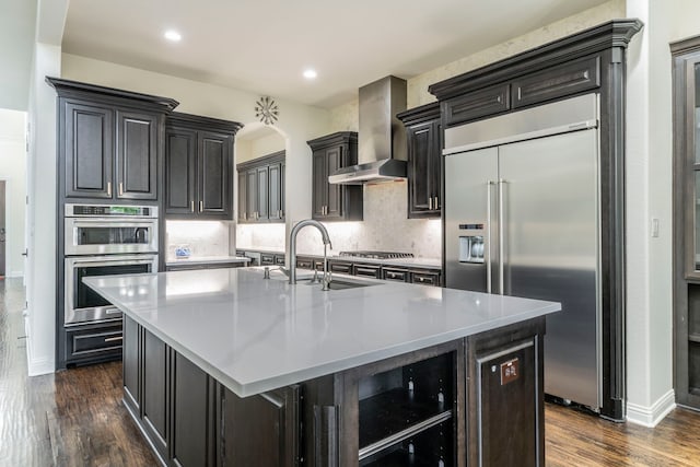 13122 Dolomite Dr, Frisco, TX 75035 - kitchen with appliances with stainless steel finishes, wall chimney range hood, dark wood-type flooring, a kitchen island with sink, and tasteful backsplash