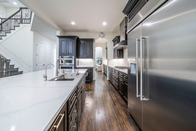 13122 Dolomite Dr, Frisco, TX 75035 - kitchen featuring appliances with stainless steel finishes, dark wood-style floors, recessed lighting, wall chimney range hood, and light stone counters