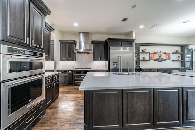 13122 Dolomite Dr, Frisco, TX 75035 - kitchen featuring stainless steel appliances, wall chimney exhaust hood, light countertops, dark wood finished floors, and recessed lighting