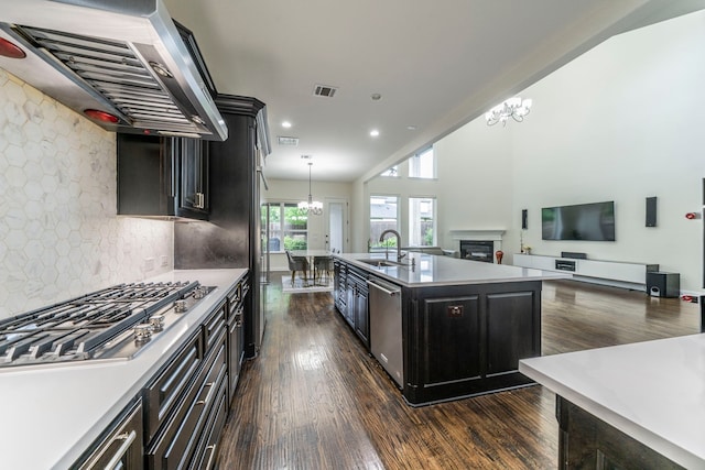 13122 Dolomite Dr, Frisco, TX 75035 - kitchen with exhaust hood, stainless steel appliances, dark wood-style flooring, decorative backsplash, and dark cabinets