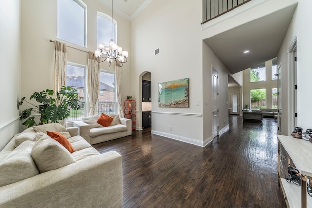 13122 Dolomite Dr, Frisco, TX 75035 - living area with arched walkways, a high ceiling, dark wood-style floors, ornamental molding, and a chandelier