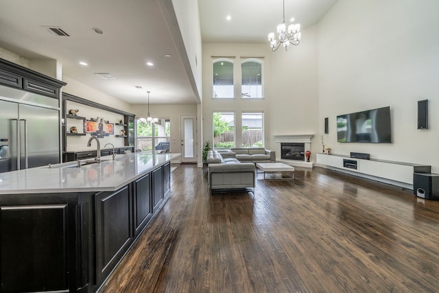 13122 Dolomite Dr, Frisco, TX 75035 - living room featuring a chandelier, dark wood-style floors, a glass covered fireplace, a towering ceiling, and recessed lighting