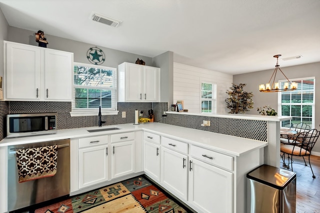 104 Nob Hill Cir, Malakoff, TX 75148 - kitchen with stainless steel appliances, a peninsula, light wood finished floors, decorative backsplash, and plenty of natural light