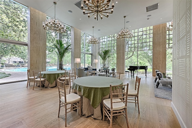 3525 Turtle Creek Blvd Unit 4E, Dallas, TX 75219 - dining space featuring a chandelier, a high ceiling, a wall of windows, and light wood-style flooring