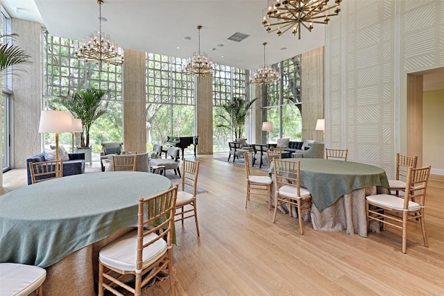 3525 Turtle Creek Blvd Unit 4E, Dallas, TX 75219 - dining room featuring a chandelier, a towering ceiling, wood finished floors, and floor to ceiling windows