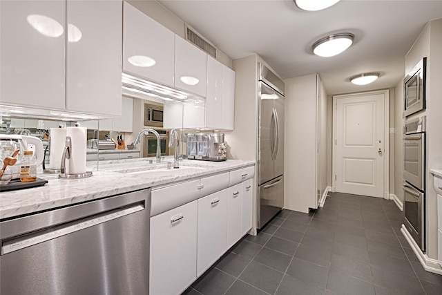 3525 Turtle Creek Blvd Unit 4E, Dallas, TX 75219 - kitchen featuring built in appliances, white cabinets, dark tile patterned floors, and light stone countertops