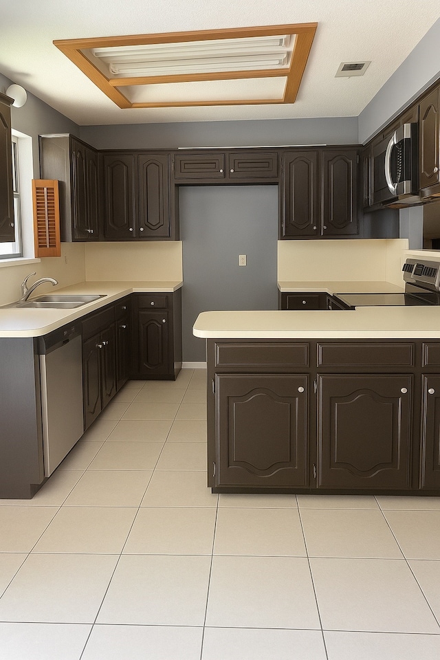 202 Modene Ave, Waxahachie, TX 75165 - kitchen with appliances with stainless steel finishes, dark brown cabinets, light tile patterned flooring, and light countertops