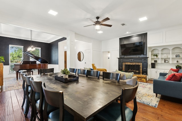 10216 Shadow Way, Dallas, TX 75243 - dining area featuring a fireplace, wood finished floors, a ceiling fan, recessed lighting, and a decorative wall