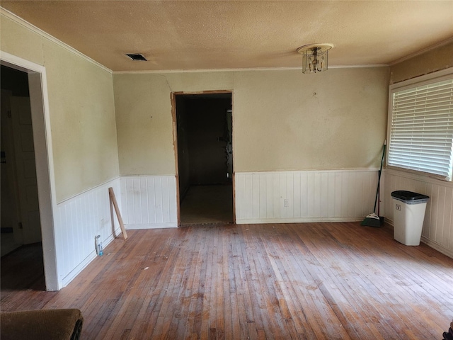 1000 Harrison St, Commerce, TX 75428 - spare room with hardwood / wood-style floors, a wainscoted wall, a textured ceiling, and crown molding