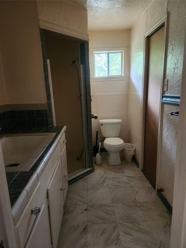 1000 Harrison St, Commerce, TX 75428 - bathroom with a shower stall, vanity, a textured wall, and a textured ceiling