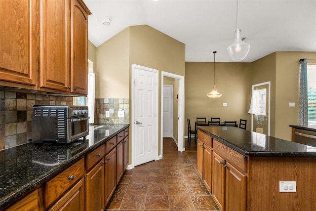 6505 Taprock Dr, Mckinney, TX 75070 - kitchen featuring backsplash, brown cabinets, pendant lighting, dark stone counters, and a kitchen island
