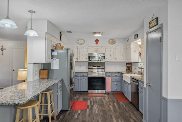 180 Vz County Road 4202, Canton, TX 75103 - kitchen featuring stainless steel appliances, a peninsula, dark wood-type flooring, light stone countertops, and a kitchen breakfast bar