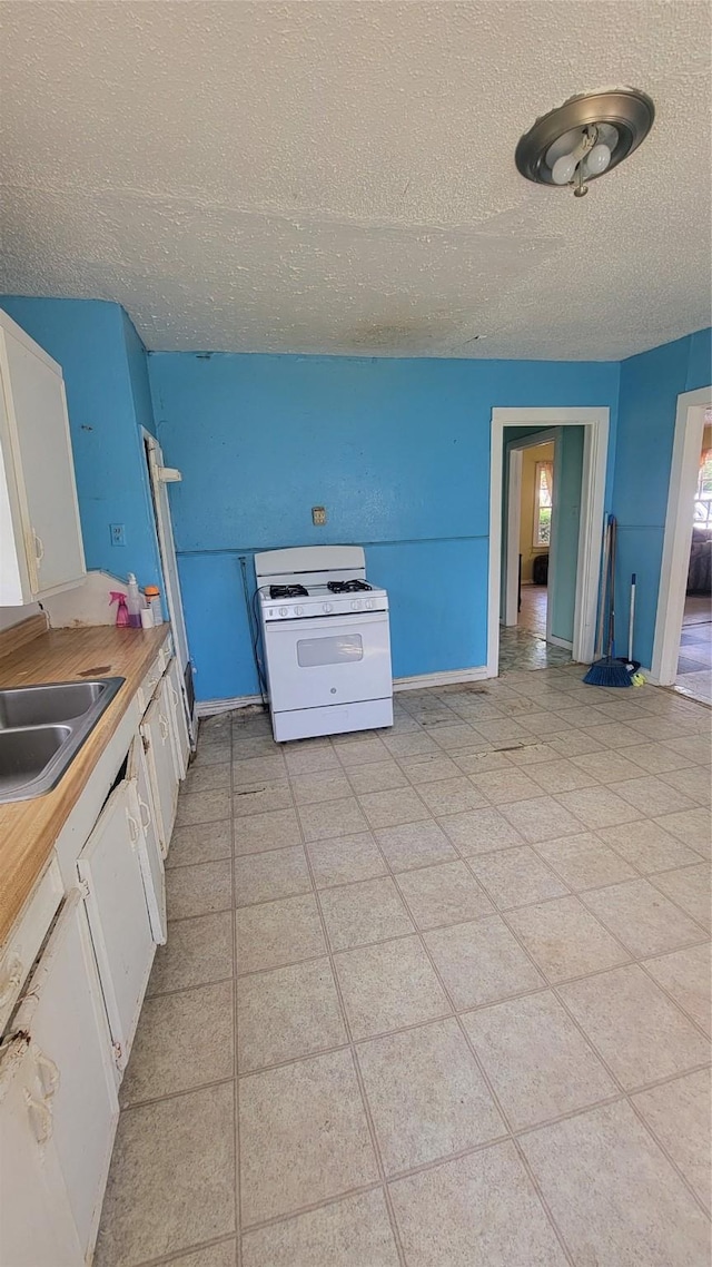 401 Lawrence Ave, Terrell, TX 75160 - kitchen with white range with gas stovetop, a textured ceiling, white cabinets, and light countertops