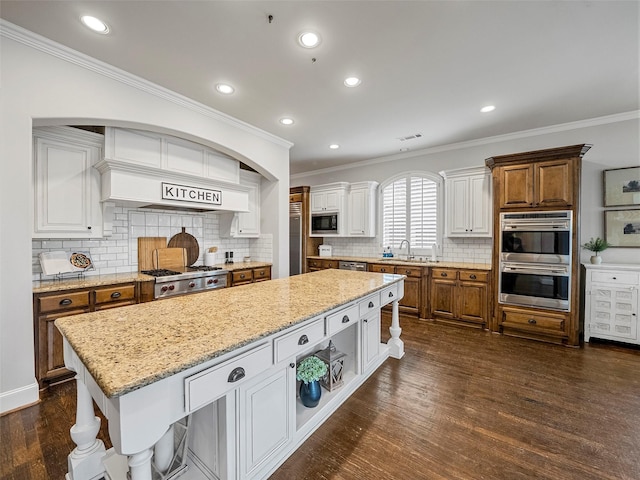 3309 Laurel Fork Dr, Mckinney, TX 75070 - kitchen featuring built in appliances, crown molding, a kitchen island, tasteful backsplash, and white cabinetry