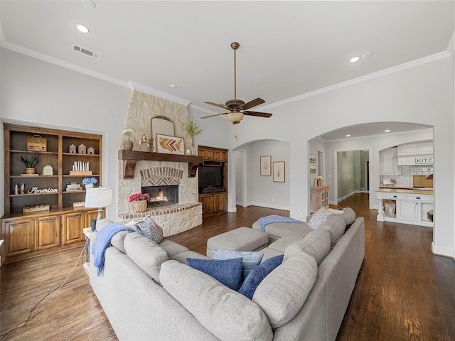 3309 Laurel Fork Dr, Mckinney, TX 75070 - living room featuring arched walkways, ceiling fan, wood finished floors, crown molding, and a large fireplace