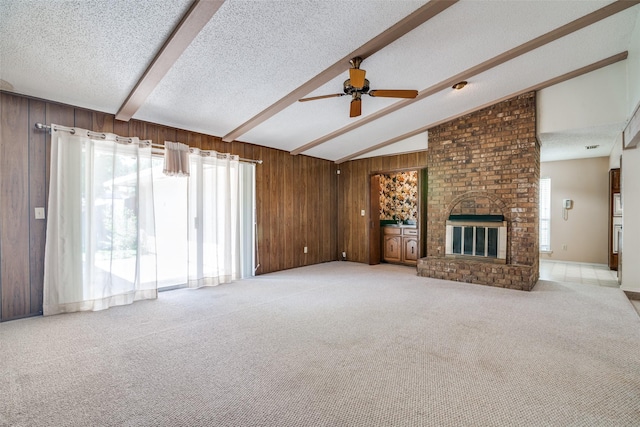 406 Los Santos Dr, Garland, TX 75043 - unfurnished living room featuring a ceiling fan, a textured ceiling, light carpet, wooden walls, and a fireplace