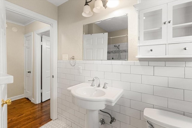 3605 Stadium Dr, Fort Worth, TX 76109 - bathroom featuring a tile shower, crown molding, tile walls, and wood finished floors