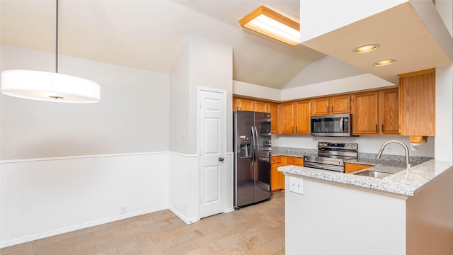 2512 Woodhaven Dr, Flower Mound, TX 75028 - kitchen with appliances with stainless steel finishes, light stone counters, a peninsula, brown cabinets, and a wainscoted wall
