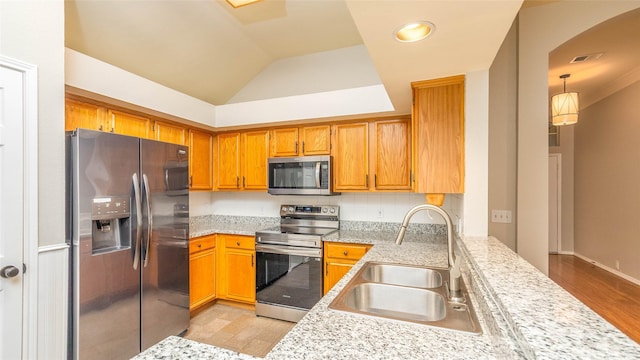 2512 Woodhaven Dr, Flower Mound, TX 75028 - kitchen featuring stainless steel appliances, brown cabinets, arched walkways, lofted ceiling, and light wood-style flooring