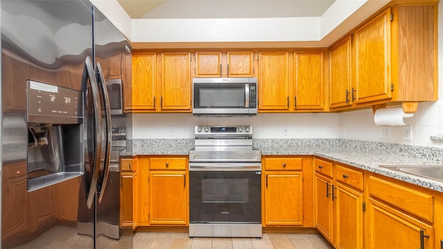 2512 Woodhaven Dr, Flower Mound, TX 75028 - kitchen featuring appliances with stainless steel finishes, brown cabinets, and light stone countertops