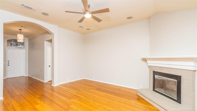 2512 Woodhaven Dr, Flower Mound, TX 75028 - unfurnished living room with arched walkways, light wood finished floors, ceiling fan, and a fireplace