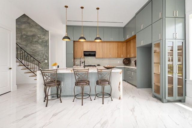 1022 Bow St, Rockwall, TX 75087 - kitchen featuring light marble finish floors, tasteful backsplash, light countertops, and an island with sink