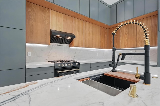 1022 Bow St, Rockwall, TX 75087 - kitchen with gas stove, exhaust hood, tasteful backsplash, freestanding refrigerator, and light stone counters