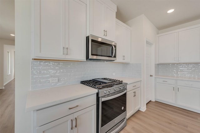 1502 Salem Dr, Forney, TX 75126 - kitchen featuring appliances with stainless steel finishes, light wood-style floors, light countertops, white cabinetry, and decorative backsplash